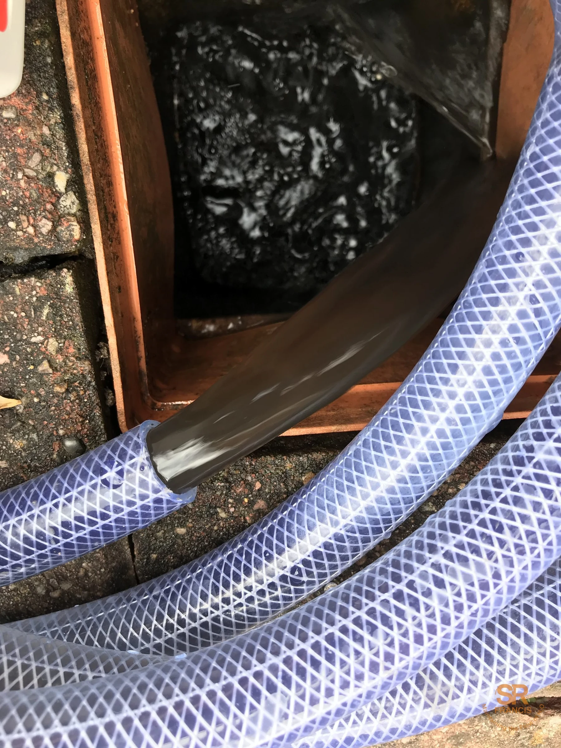Dirty black heating system water being flushed through clear hose